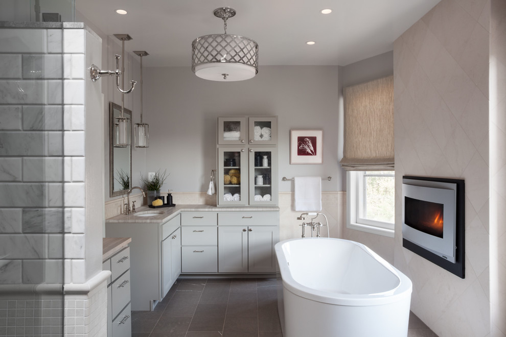 Inspiration for a large transitional master white tile and marble tile slate floor and gray floor freestanding bathtub remodel in DC Metro with an undermount sink, shaker cabinets, gray cabinets, gray walls, soapstone countertops and a hinged shower door