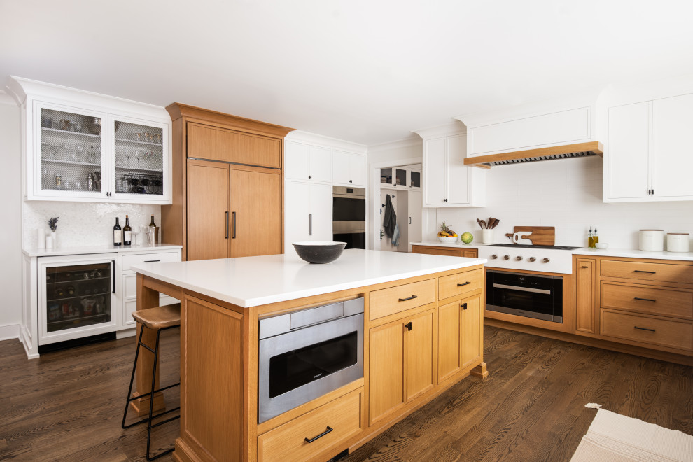 Photo of a medium sized traditional l-shaped kitchen/diner in New York with a built-in sink, beaded cabinets, white cabinets, composite countertops, white splashback, porcelain splashback, stainless steel appliances, medium hardwood flooring, an island and white worktops.