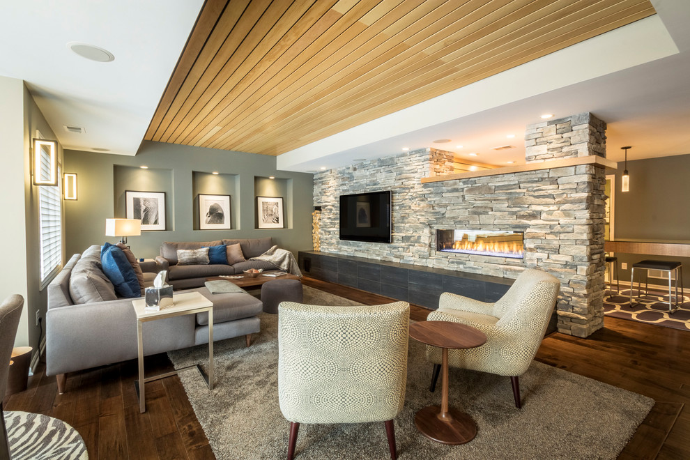This is an example of a contemporary enclosed family room in Minneapolis with a ribbon fireplace, a stone fireplace surround, grey walls, dark hardwood floors, a wall-mounted tv and brown floor.