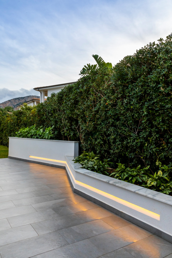 Идея дизайна: большой солнечный, весенний участок и сад на переднем дворе в современном стиле с хорошей освещенностью, настилом и с каменным забором
