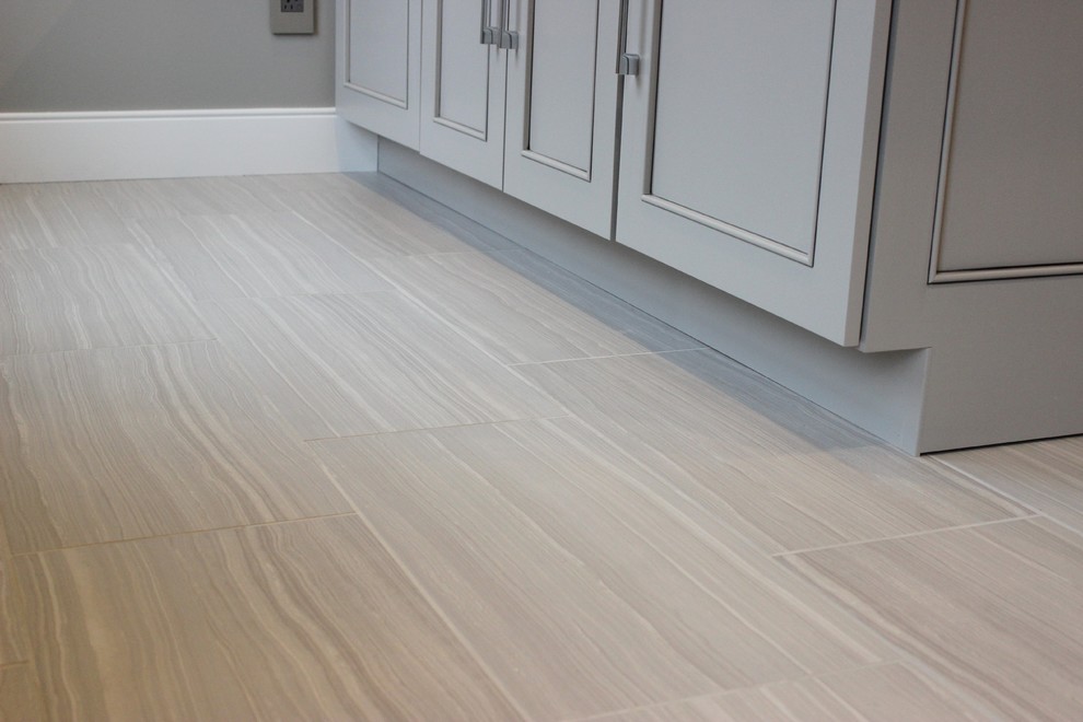 Photo of a large transitional l-shaped dedicated laundry room in Chicago with an undermount sink, flat-panel cabinets, grey cabinets, quartz benchtops, grey walls, ceramic floors and a side-by-side washer and dryer.