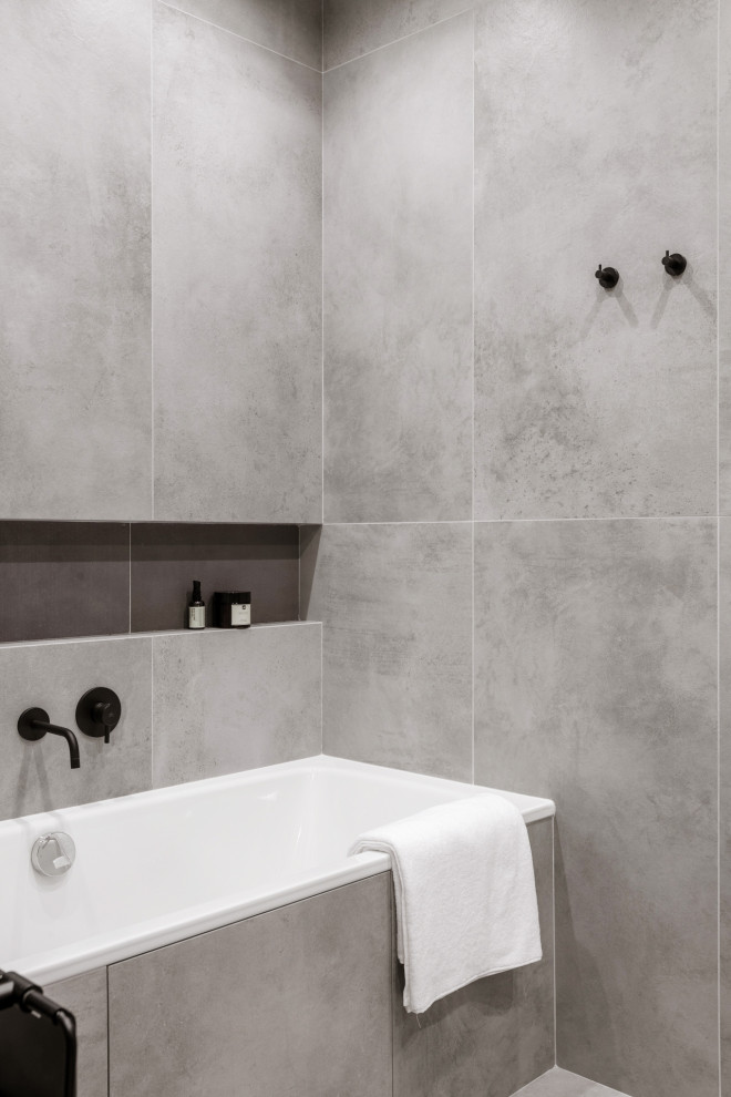 Пример оригинального дизайна: главная, серо-белая ванная комната среднего размера в современном стиле с плоскими фасадами, серыми фасадами, ванной в нише, душем в нише, инсталляцией, серой плиткой, керамогранитной плиткой, серыми стенами, полом из керамогранита, подвесной раковиной, серым полом, душем с раздвижными дверями, белой столешницей, зеркалом с подсветкой, тумбой под одну раковину и подвесной тумбой