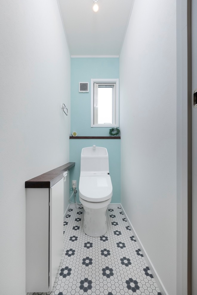 This is an example of an asian powder room in Other with flat-panel cabinets, white cabinets, blue walls, multi-coloured floor, a one-piece toilet and vinyl floors.