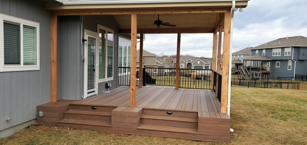 Design ideas for a backyard verandah in Kansas City with a roof extension and mixed railing.
