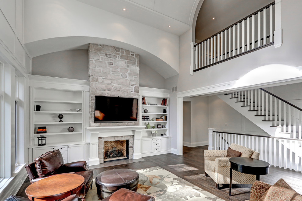 Design ideas for a large transitional open concept family room in Toronto with grey walls, medium hardwood floors, a standard fireplace, a stone fireplace surround, a wall-mounted tv and brown floor.