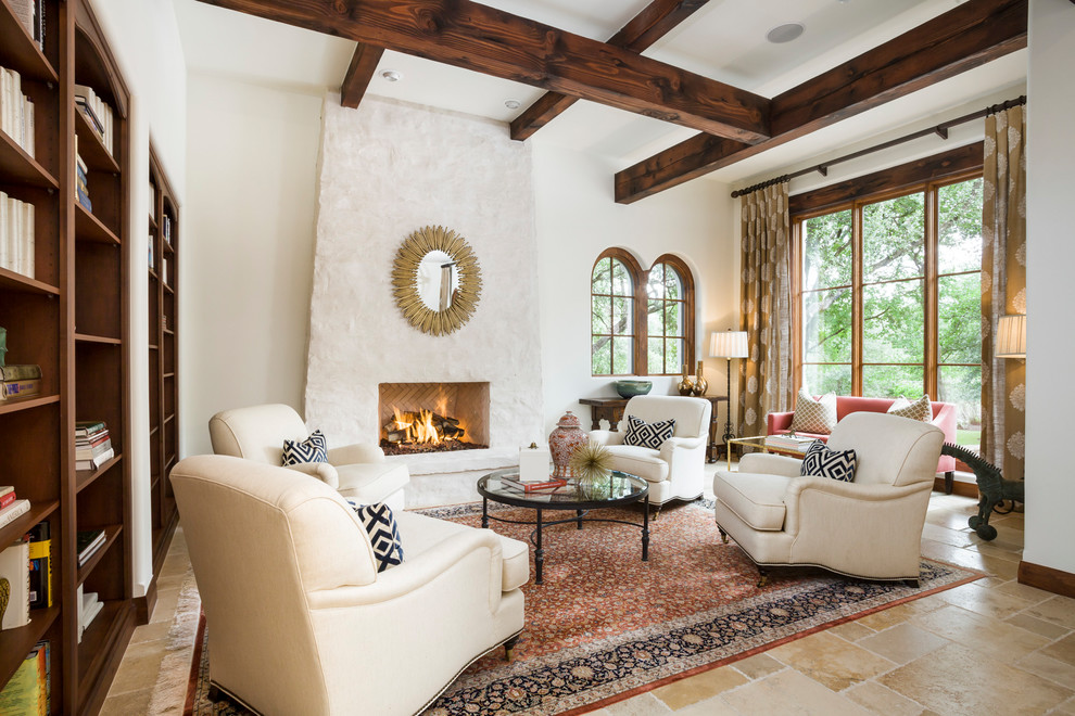 Large mediterranean living room in Austin with a library, white walls, a standard fireplace and brown floor.
