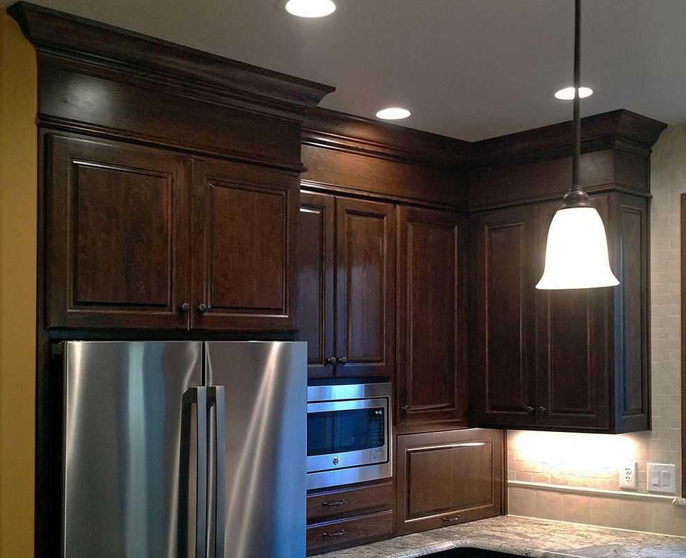 Kitchen - l-shaped kitchen idea with an integrated sink, raised-panel cabinets, brown cabinets, stainless steel appliances and an island