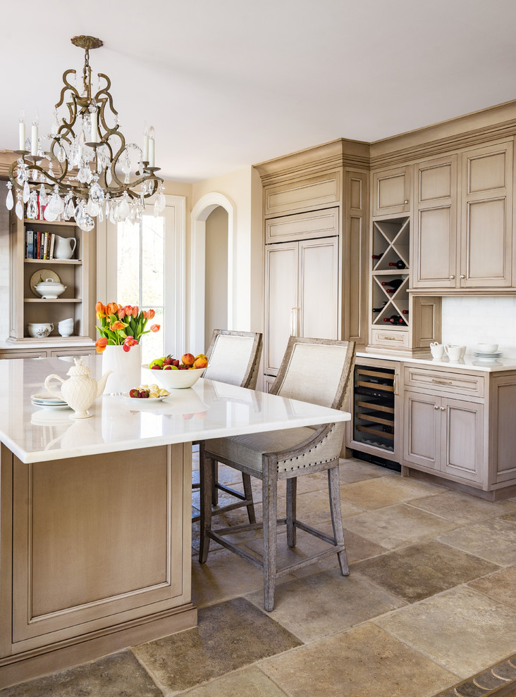 Design ideas for a traditional l-shaped kitchen in Boston with recessed-panel cabinets, white splashback, limestone floors, with island, beige floor and white benchtop.