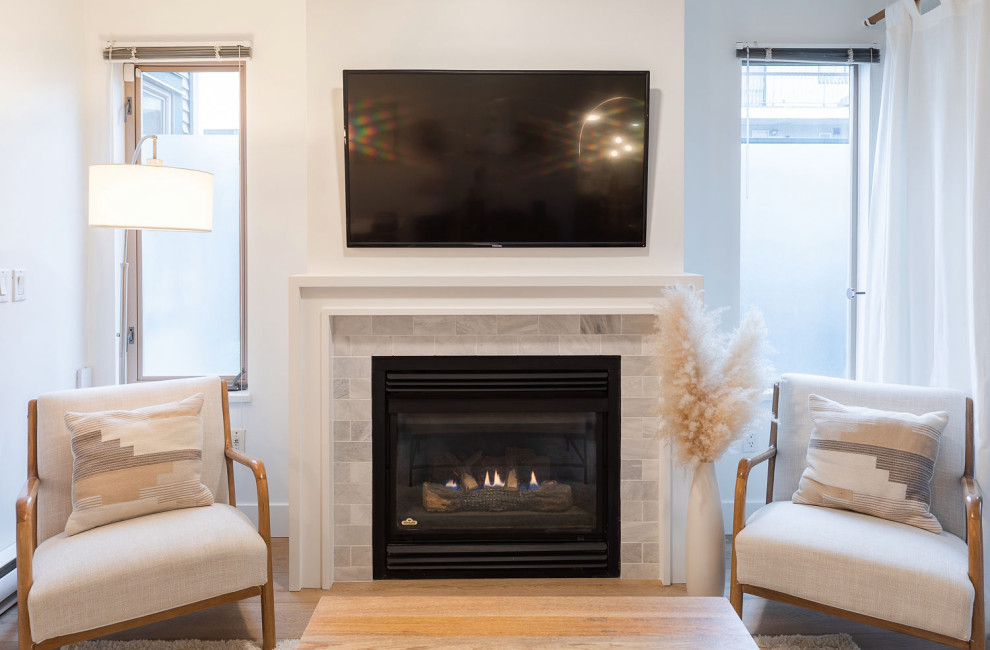 Small transitional enclosed living room in Vancouver with white walls, vinyl floors, a standard fireplace, a tile fireplace surround, a built-in media wall and brown floor.