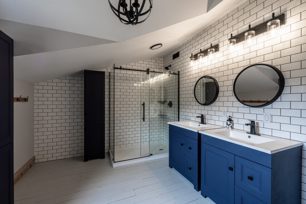 Стильный дизайн: большая главная ванная комната в стиле кантри с фасадами в стиле шейкер, синими фасадами, отдельно стоящей ванной, угловым душем, раздельным унитазом, белой плиткой, плиткой кабанчик, серыми стенами, деревянным полом, монолитной раковиной, столешницей из искусственного камня, серым полом, душем с раздвижными дверями, белой столешницей, тумбой под одну раковину, напольной тумбой и сводчатым потолком - последний тренд