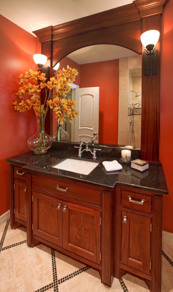 This is an example of a small traditional bathroom in Houston with an undermount sink, medium wood cabinets, granite benchtops, an alcove tub, a shower/bathtub combo, a two-piece toilet, beige tile, stone tile, red walls, travertine floors and beaded inset cabinets.