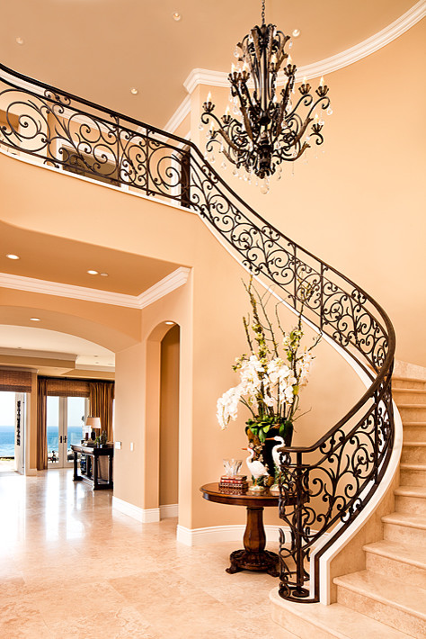 Design ideas for a large mediterranean travertine curved staircase in Orange County with travertine risers and metal railing.
