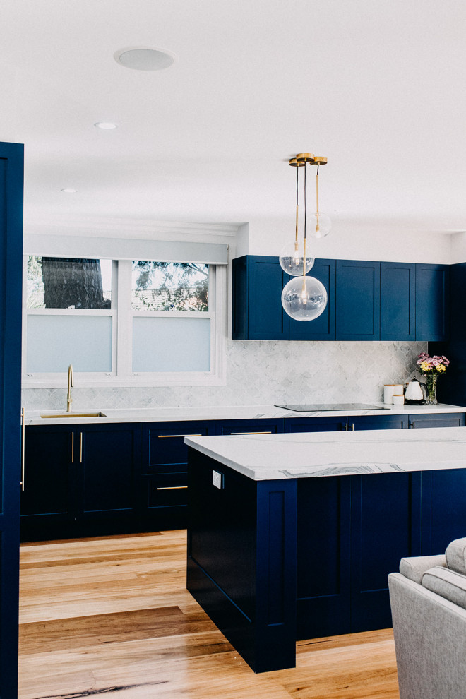 Photo of a large traditional kitchen in Sydney with an undermount sink, shaker cabinets, blue cabinets, marble splashback, light hardwood floors and with island.