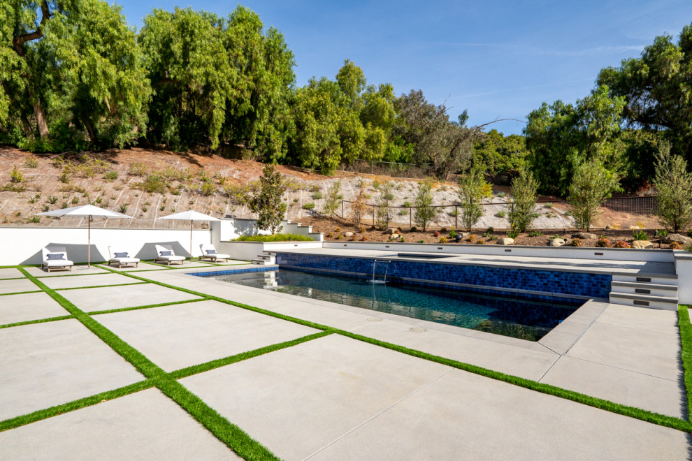Ejemplo de piscinas y jacuzzis campestres extra grandes rectangulares en patio trasero con adoquines de hormigón