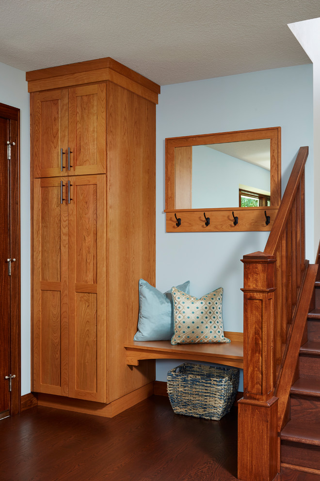 This is an example of a transitional mudroom with blue walls and dark hardwood floors.