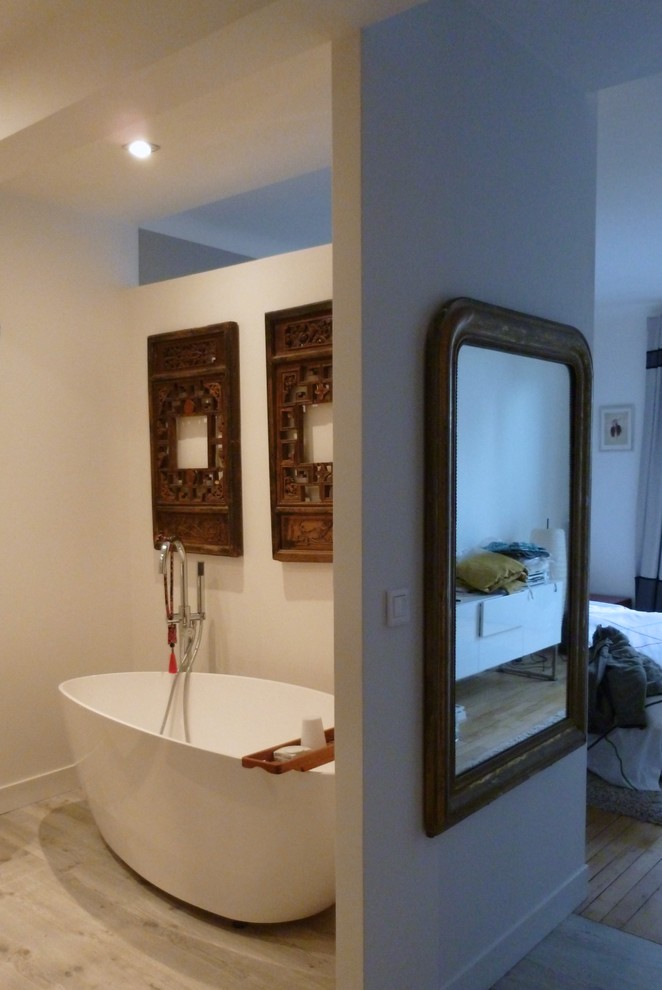 Photo of a mid-sized contemporary master bathroom in Paris with flat-panel cabinets, black cabinets, a freestanding tub, a curbless shower, a two-piece toilet, beige tile, ceramic tile, white walls, laminate floors, a trough sink, beige floor and a sliding shower screen.