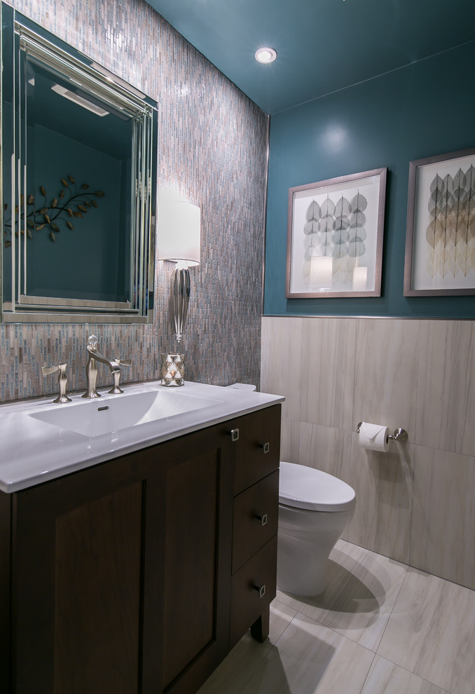 Photo of a mid-sized contemporary powder room in San Francisco with furniture-like cabinets, dark wood cabinets, a two-piece toilet, multi-coloured tile, mosaic tile, blue walls, porcelain floors, an integrated sink, grey floor, engineered quartz benchtops and white benchtops.