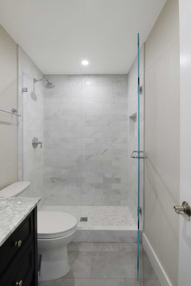 Modern inredning av ett mellanstort flerfärgad flerfärgat badrum med dusch, med luckor med infälld panel, svarta skåp, en dusch i en alkov, en toalettstol med separat cisternkåpa, vit kakel, porslinskakel, vita väggar, klinkergolv i porslin, ett undermonterad handfat, bänkskiva i akrylsten, flerfärgat golv och dusch med gångjärnsdörr