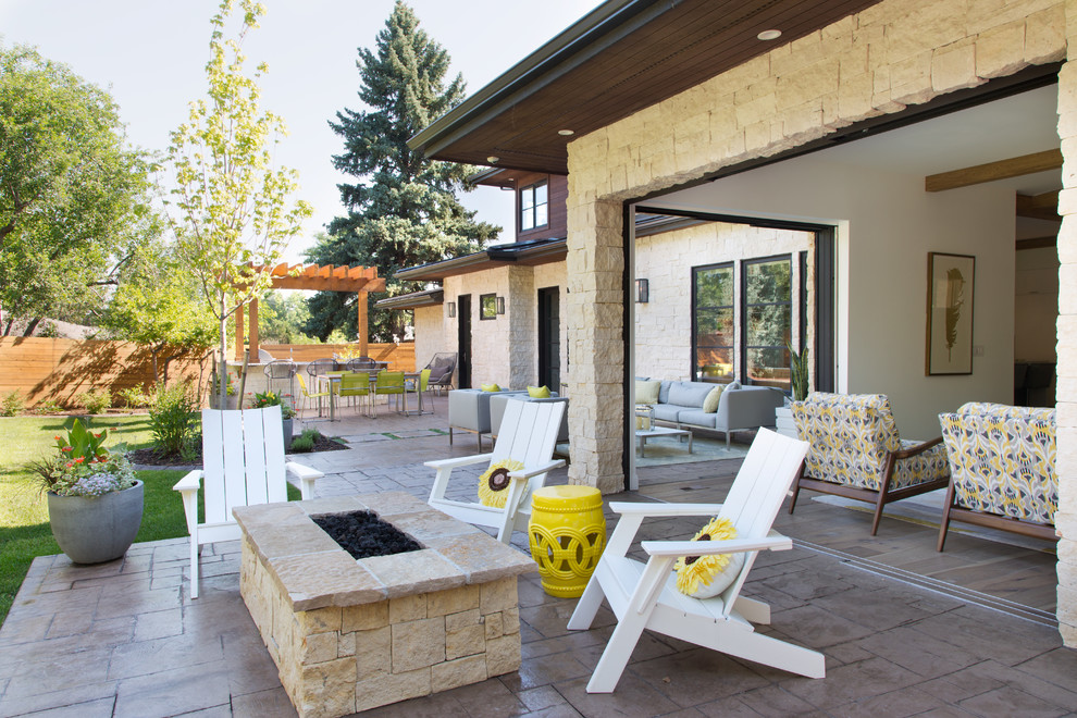 This is an example of a transitional backyard patio in Denver with a fire feature and a roof extension.