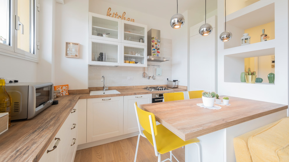 Scandinavian l-shaped kitchen in Milan with a drop-in sink, raised-panel cabinets, white cabinets, wood benchtops, white splashback, medium hardwood floors, a peninsula, brown floor and brown benchtop.