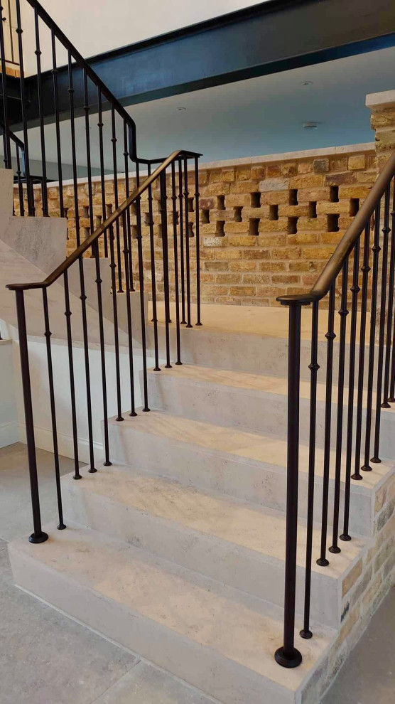 На фото: лестница на больцах, среднего размера в стиле модернизм с ступенями из травертина, подступенками из травертина и металлическими перилами