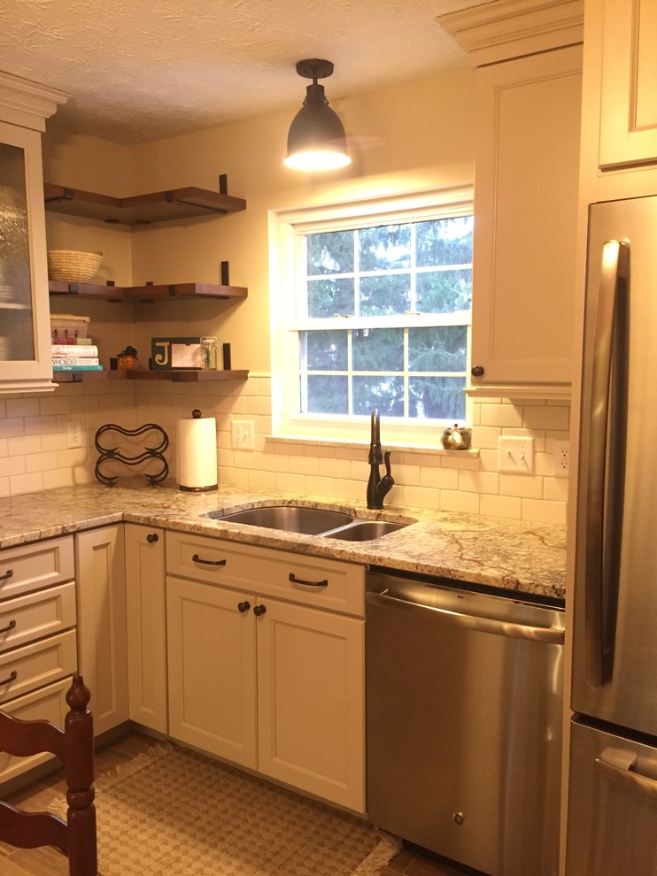 Mountain style brown floor kitchen photo in Cincinnati with a double-bowl sink, raised-panel cabinets, beige cabinets, granite countertops, white backsplash, terra-cotta backsplash and stainless steel appliances