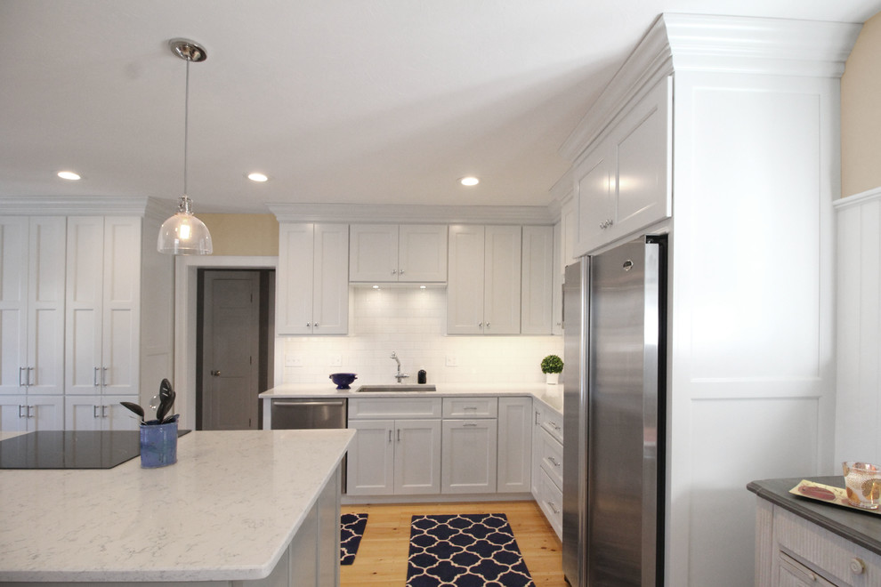 Design ideas for a large transitional l-shaped open plan kitchen in Boston with an undermount sink, shaker cabinets, white cabinets, quartz benchtops, white splashback, subway tile splashback, stainless steel appliances, light hardwood floors, with island and brown floor.