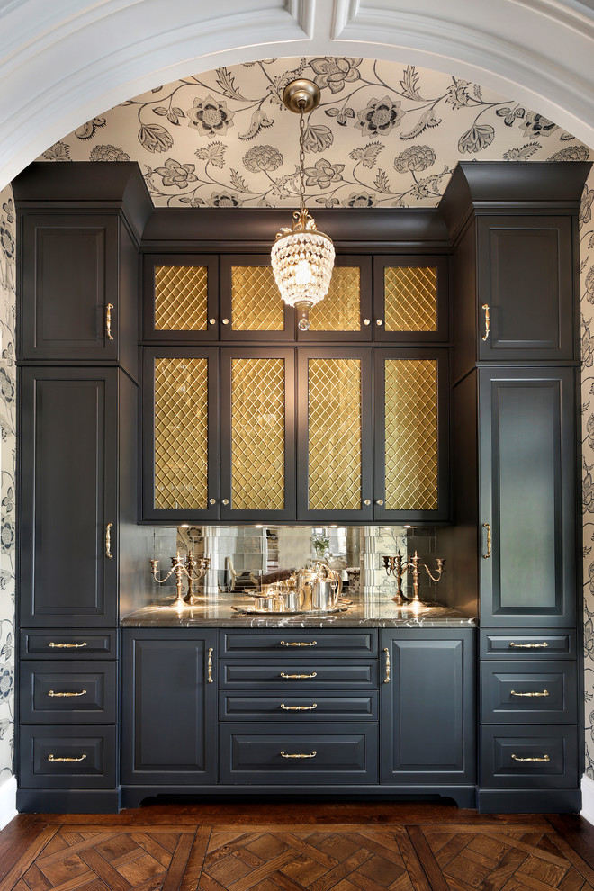 This is an example of a traditional single-wall home bar in Chicago with no sink, raised-panel cabinets, black cabinets, metal splashback, dark hardwood floors, brown floor and grey benchtop.
