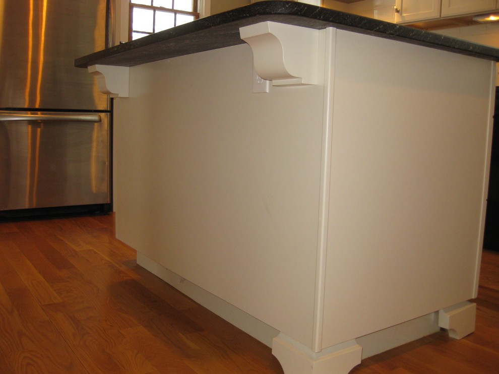 Eat-in kitchen - transitional l-shaped medium tone wood floor eat-in kitchen idea in Boston with an undermount sink, shaker cabinets, white cabinets, quartz countertops, white backsplash, ceramic backsplash, stainless steel appliances, an island and black countertops
