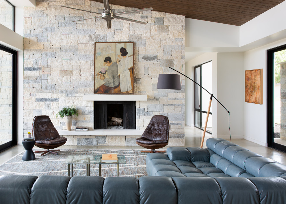 Идея дизайна: открытая гостиная комната среднего размера в современном стиле с белыми стенами, бетонным полом, стандартным камином, фасадом камина из камня, скрытым телевизором, бежевым полом, деревянным потолком и кирпичными стенами