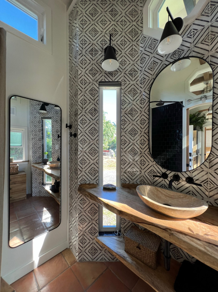 This is an example of a mid-sized country master bathroom in Hawaii with open cabinets, light wood cabinets, a corner shower, black and white tile, ceramic tile, terra-cotta floors, wood benchtops, a shower curtain, beige benchtops, a niche, a single vanity, a floating vanity and exposed beam.