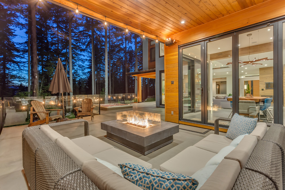 Large contemporary patio in Vancouver with a fire feature, concrete slab and a roof extension.
