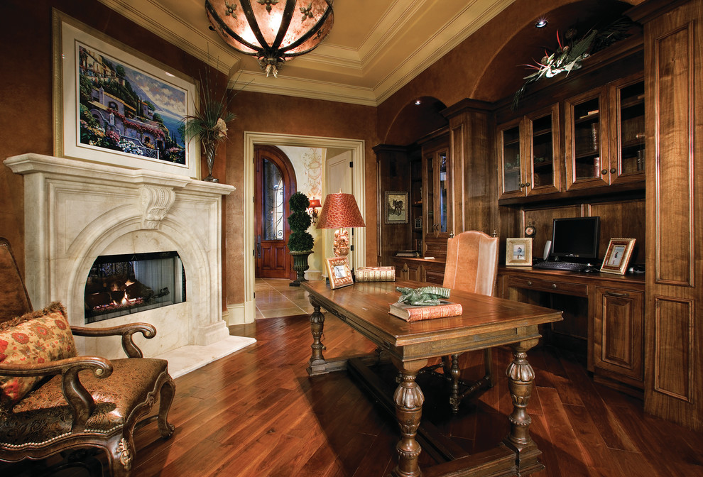 Expansive mediterranean study room in Miami with dark hardwood floors, a standard fireplace, a stone fireplace surround and a freestanding desk.
