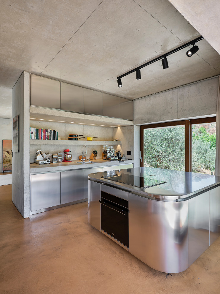 This is an example of a mid-sized contemporary open plan kitchen in Other with a drop-in sink, beaded inset cabinets, stainless steel cabinets, stainless steel benchtops, concrete floors and with island.