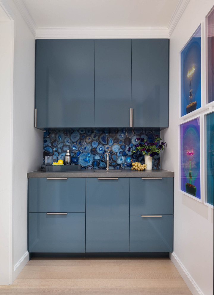 Photo of an expansive classic galley home bar in San Francisco with a submerged sink, flat-panel cabinets, blue cabinets, blue splashback, stone slab splashback, light hardwood flooring and beige floors.