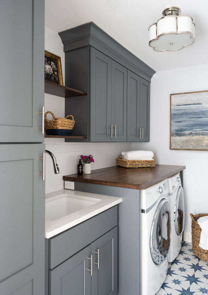 Design ideas for a classic single-wall separated utility room in Boston with a submerged sink, blue cabinets, engineered stone countertops, white splashback, metro tiled splashback, white walls, ceramic flooring, a side by side washer and dryer and white worktops.