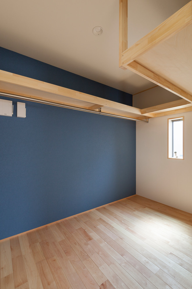 Photo of a mid-sized gender-neutral walk-in wardrobe in Tokyo with light hardwood floors and wallpaper.
