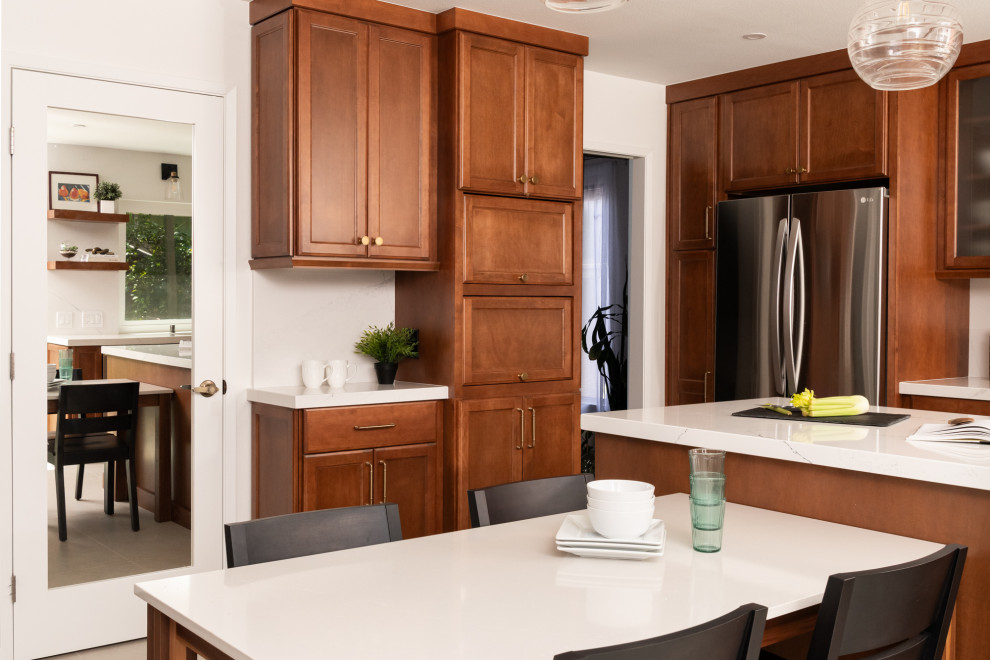 Inspiration for a transitional porcelain tile and beige floor kitchen remodel in Orange County with an undermount sink, shaker cabinets, medium tone wood cabinets, quartz countertops, white backsplash, quartz backsplash, stainless steel appliances, an island and white countertops
