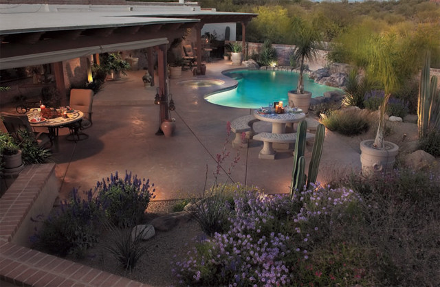 This is an example of a mid-sized backyard custom-shaped pool in Phoenix with a hot tub and concrete slab.