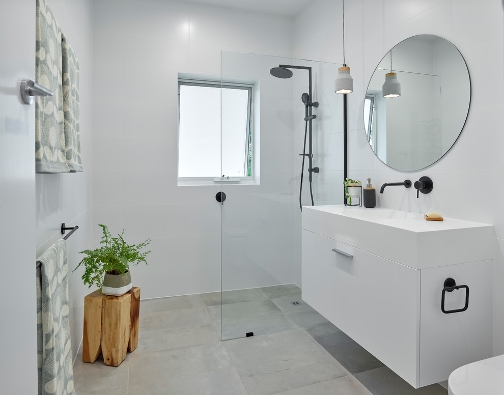 Design ideas for a mid-sized contemporary 3/4 bathroom in Other with an open shower, a two-piece toilet, white tile, porcelain tile, white walls, porcelain floors, an integrated sink, grey floor, an open shower, flat-panel cabinets, white cabinets, solid surface benchtops and white benchtops.