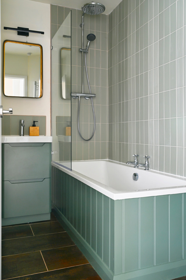 Idéer för ett litet minimalistiskt en-suite badrum, med släta luckor, gröna skåp, en dusch/badkar-kombination, en toalettstol med separat cisternkåpa, grön kakel, keramikplattor, vita väggar, klinkergolv i keramik, ett integrerad handfat, brunt golv och dusch med gångjärnsdörr