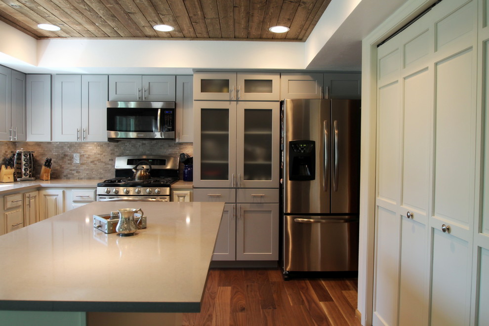 Inspiration for a large transitional l-shaped medium tone wood floor eat-in kitchen remodel in Denver with an undermount sink, shaker cabinets, gray cabinets, quartz countertops, gray backsplash, stone tile backsplash, stainless steel appliances and an island