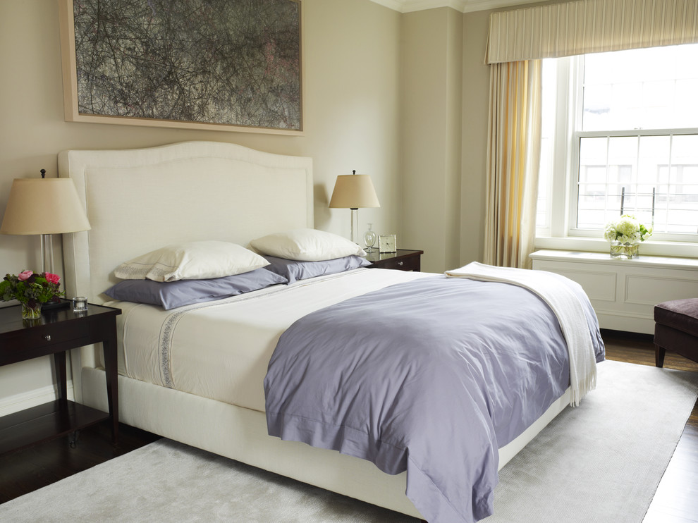 Traditional bedroom in New York with beige walls and dark hardwood floors.