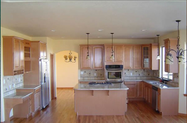 Inspiration for an u-shaped light wood floor enclosed kitchen remodel in Denver with raised-panel cabinets, light wood cabinets, beige backsplash, stainless steel appliances and an island