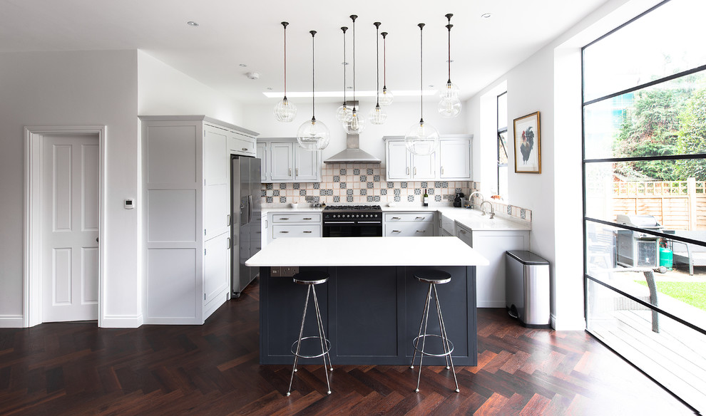 This is an example of a mid-sized traditional u-shaped open plan kitchen in London with a farmhouse sink, shaker cabinets, grey cabinets, dark hardwood floors and with island.
