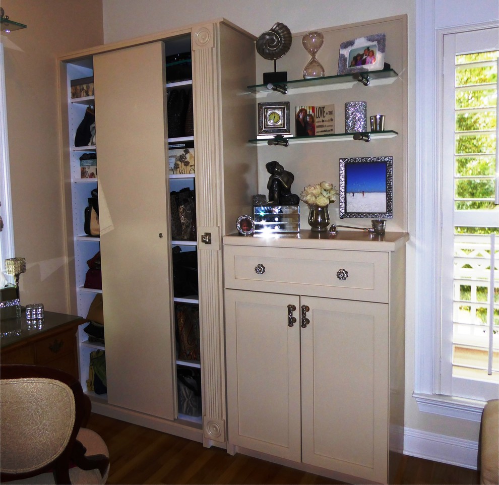 Photo of a mid-sized beach style women's built-in wardrobe in Miami with shaker cabinets, beige cabinets and medium hardwood floors.