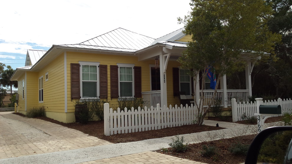 Mid-sized beach style one-storey yellow exterior in Jacksonville with vinyl siding and a gable roof.