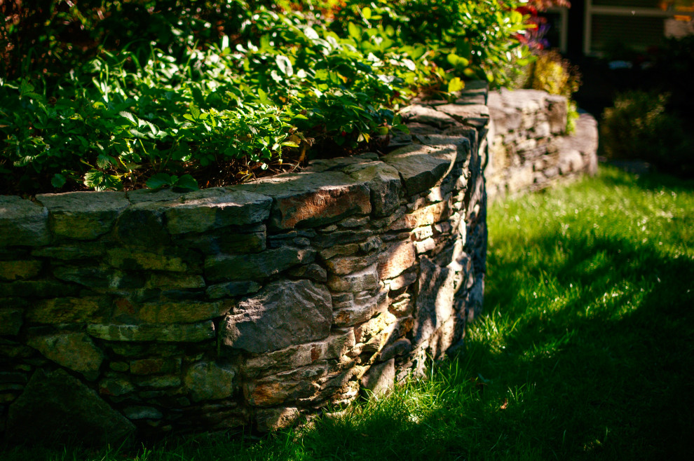 Inspiration for a rustic back partial sun garden in Vancouver with a retaining wall, natural stone paving and a wood fence.