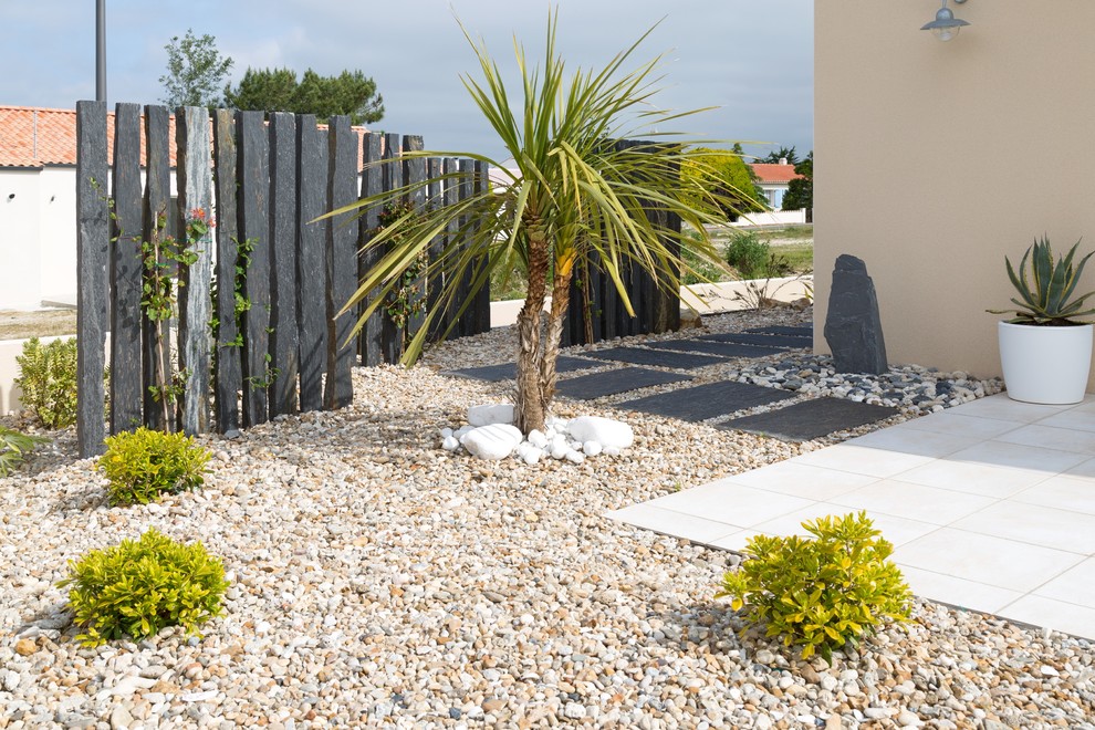 Small beach style side yard partial sun driveway in Nantes with a container garden and gravel for spring.