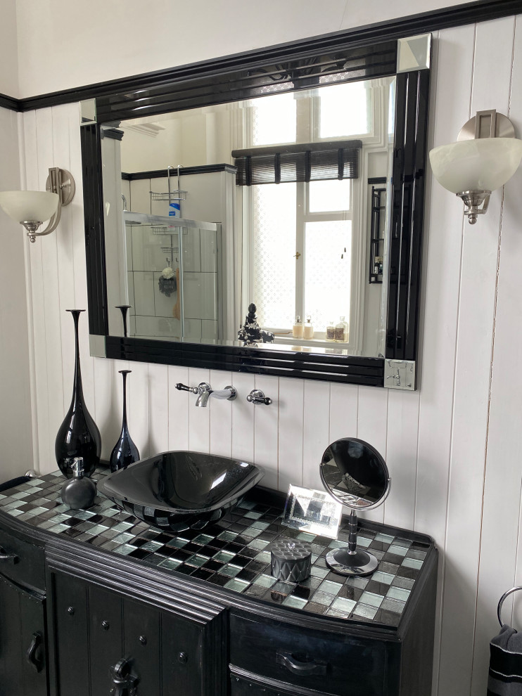 Photo of a large transitional kids bathroom in Sussex with flat-panel cabinets, black cabinets, a claw-foot tub, an alcove shower, a one-piece toilet, black and white tile, ceramic tile, grey walls, marble floors, glass benchtops, multi-coloured floor, a sliding shower screen, multi-coloured benchtops, a niche, a single vanity, a built-in vanity, planked wall panelling, a vessel sink and vaulted.